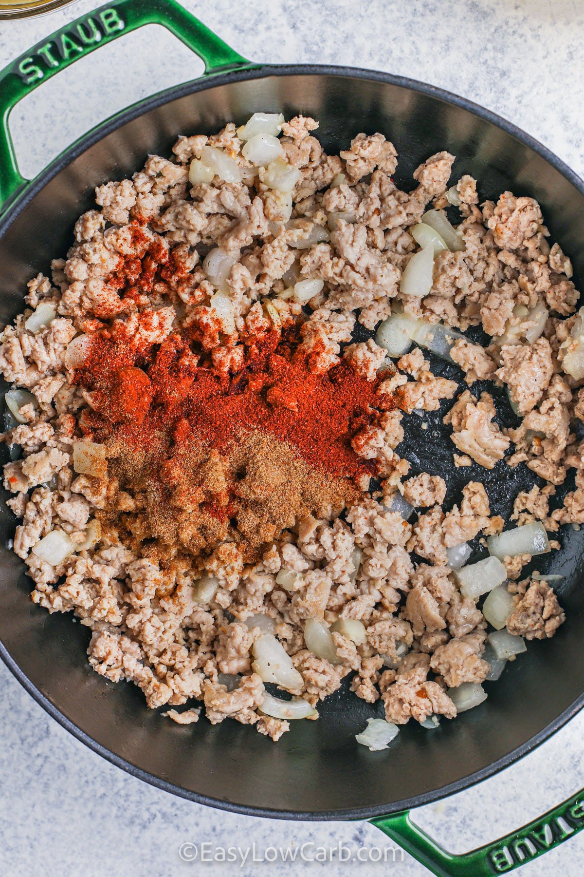 Customize this keto white chicken chili with your favorite low-carb toppings to make it even more delicious. Try shredded cheese, avocado slices, sour cream, or fresh cilantro on top for added flavor and texture. The creamy, spicy base with ground chicken, peppers, and green chilies pairs perfectly with these toppings, making it a versatile, hearty, and satisfying meal. Perfect for keto-friendly lunches, dinners, or meal prep, it’s a recipe you’ll return to again and again. #easylowcarb adding seasonings to chicken and onions to make Keto White Chicken Chili