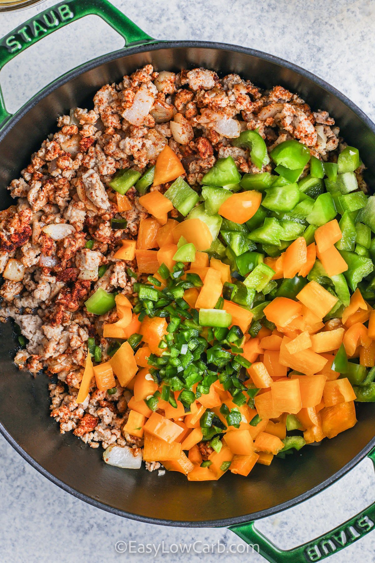 Cream cheese and heavy cream give this keto white chicken chili its luxuriously creamy, velvety texture, making every bite indulgent yet perfectly keto-friendly. Ground chicken simmers with bell peppers, jalapeño, and green chilies for a savory, flavorful experience. Spices like chili powder, cumin, and garlic powder enhance the taste, turning a simple skillet meal into a rich, comforting, low-carb dish ideal for cozy nights or batch cooking. #easylowcarb adding peppers to ingredients to make Keto White Chicken Chili