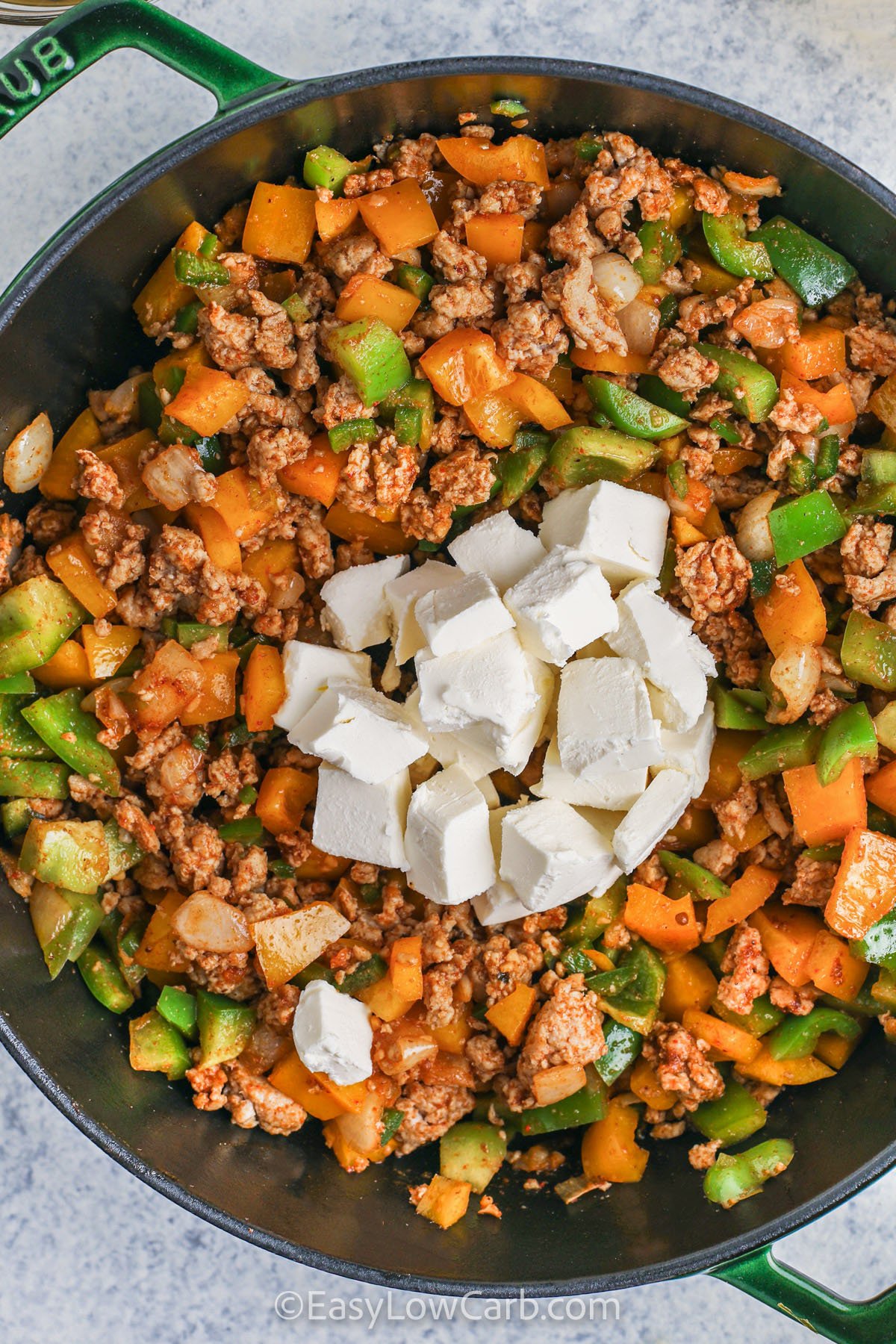 This keto white chicken chili is a protein-packed, low-carb dish ideal for anyone following a keto or low-carb lifestyle. Ground chicken provides hearty protein, while creamy cheese and heavy cream create richness without the carbs. With bell peppers, jalapeño, and green chilies adding flavor and texture, this chili is satisfying, nutritious, and keeps you full longer. It’s an easy, comforting dish perfect for dinner or meal prep. #easylowcarb adding cream cheese to ingredients to make Keto White Chicken Chili