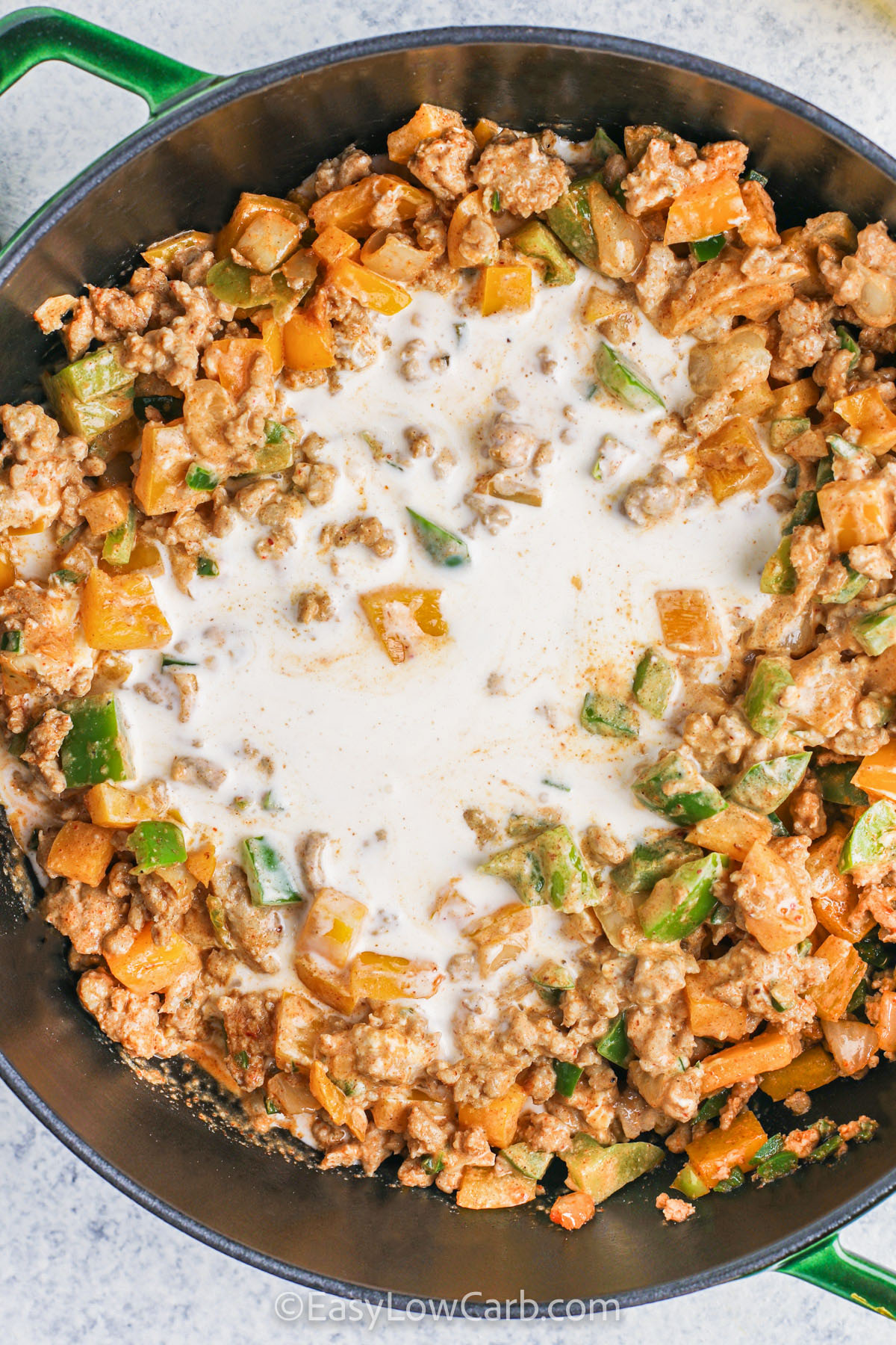 The flavor of this keto white chicken chili comes from a perfect blend of spices like chili powder, cumin, and garlic powder. Ground chicken and sautéed onions absorb these spices beautifully before being combined with bell peppers, jalapeño, and green chilies. Cream cheese and heavy cream melt into a silky sauce, creating a satisfying, low-carb chili that’s full of warmth and depth, making it a meal the whole family will love on chilly evenings. #easylowcarb adding milk to ingredients to make Keto White Chicken Chili