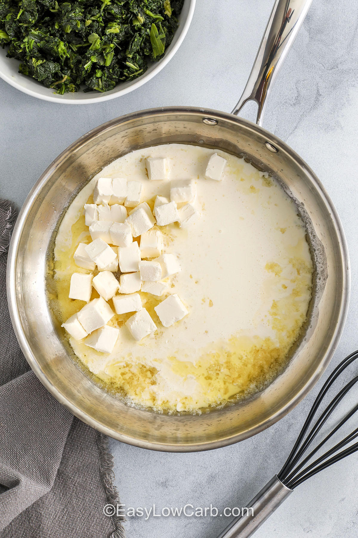 Spinach casserole brings a simple blend of creamed spinach, smooth cream, and lots of cheese for a baked side that tastes warm and comforting. The mix turns rich and soft as it melts together and feels old-fashioned in the best way. It works for any dinner and fits well on a holiday table or potluck spread. This recipe makes cozy flavor easy to enjoy and pairs nicely with almost any main dish. #easylowcarb adding ingredients together in pan to make Spinach Casserole