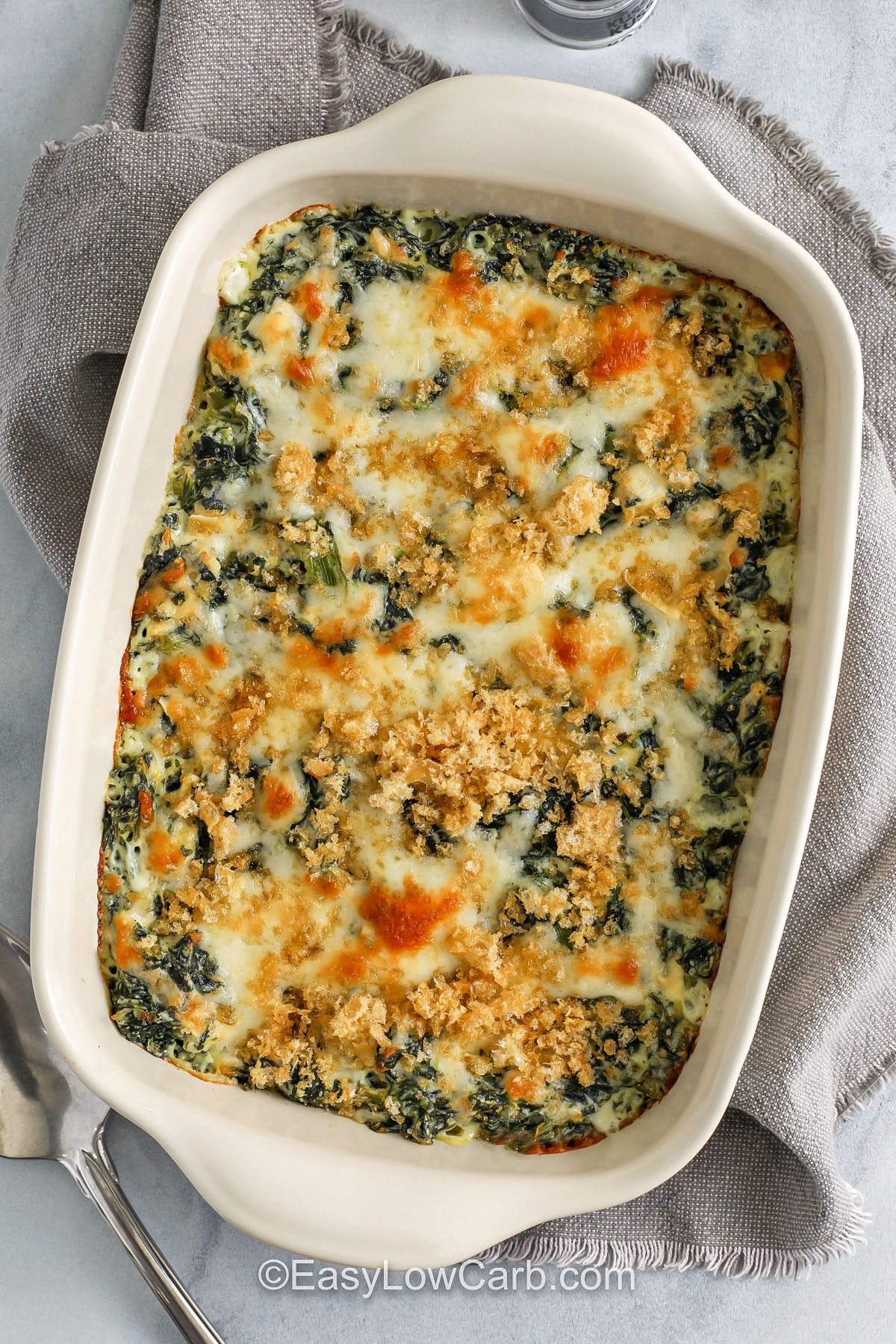Spinach casserole is a simple way to serve creamed spinach in a baked dish that feels cozy and tastes delicious. The smooth mix melts together and creates a comforting flavor that works well for a holiday dinner or potluck. It makes a great side for chicken or beef and adds a cheesy touch to any menu. This recipe brings rich taste and creamy texture together in a way that feels special but is still easy. #easylowcarb baked Spinach Casserole in a casserole dish