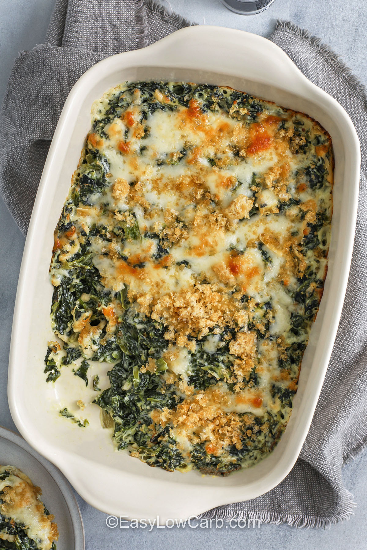 Spinach casserole mixes creamed spinach, cream, and cheese into a baked dish filled with warm comfort and simple flavor. The creamy texture and rich taste make it feel like an old-fashioned classic that works for any dinner. It fits well on a holiday table or potluck and gives a cheesy boost to the meal. This recipe makes a tasty side that blends veggies, cream, and cheese into a smooth and satisfying dish. #easylowcarb Spinach Casserole with a portion missing