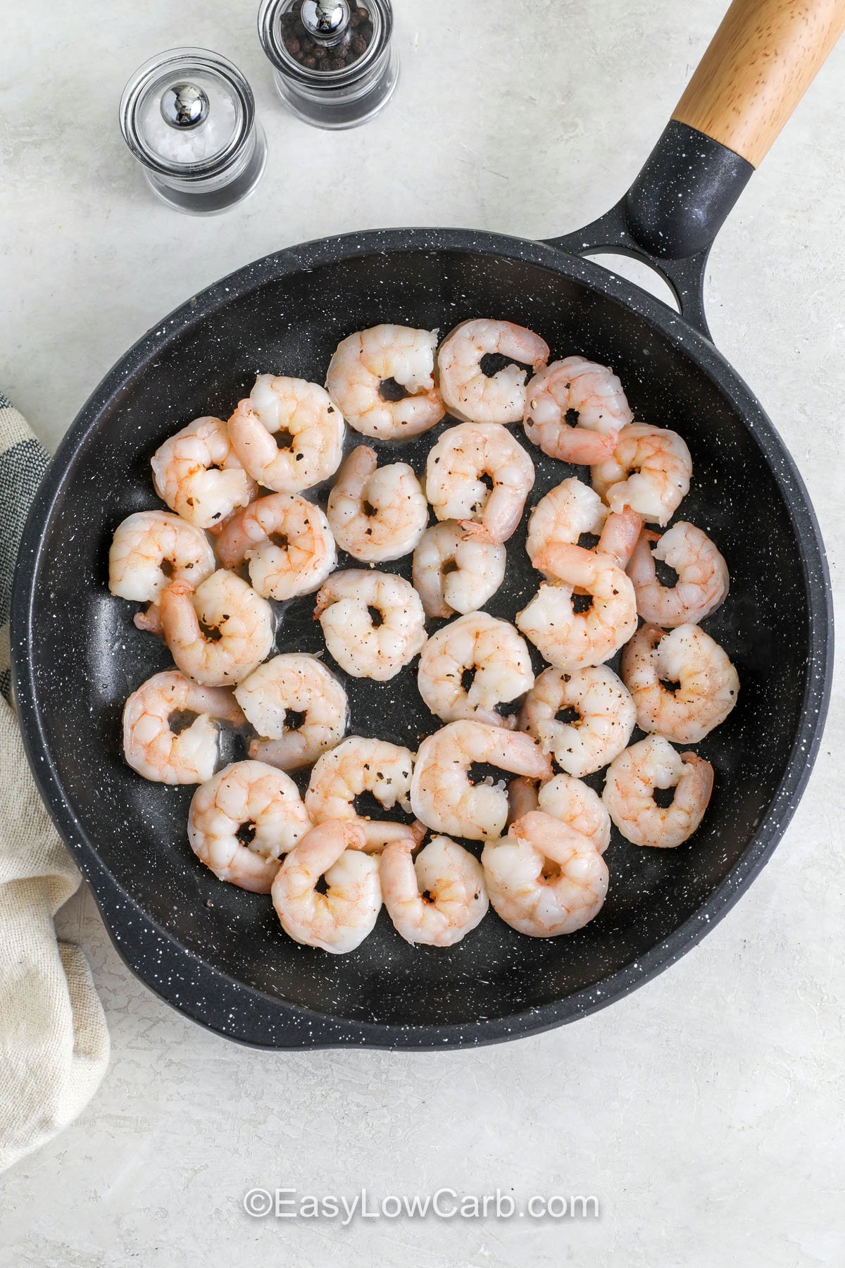 Make creamy Tuscan shrimp for a rich skillet dinner that is low carb and full of flavor. The sauce is built from butter, garlic, Italian seasoning, cream, and broth, then finished with Parmesan for a smooth, savory taste. Sun-dried tomatoes bring a tangy pop, and baby spinach. #easylowcarb shrimp in pan to make Creamy Tuscan Shrimp