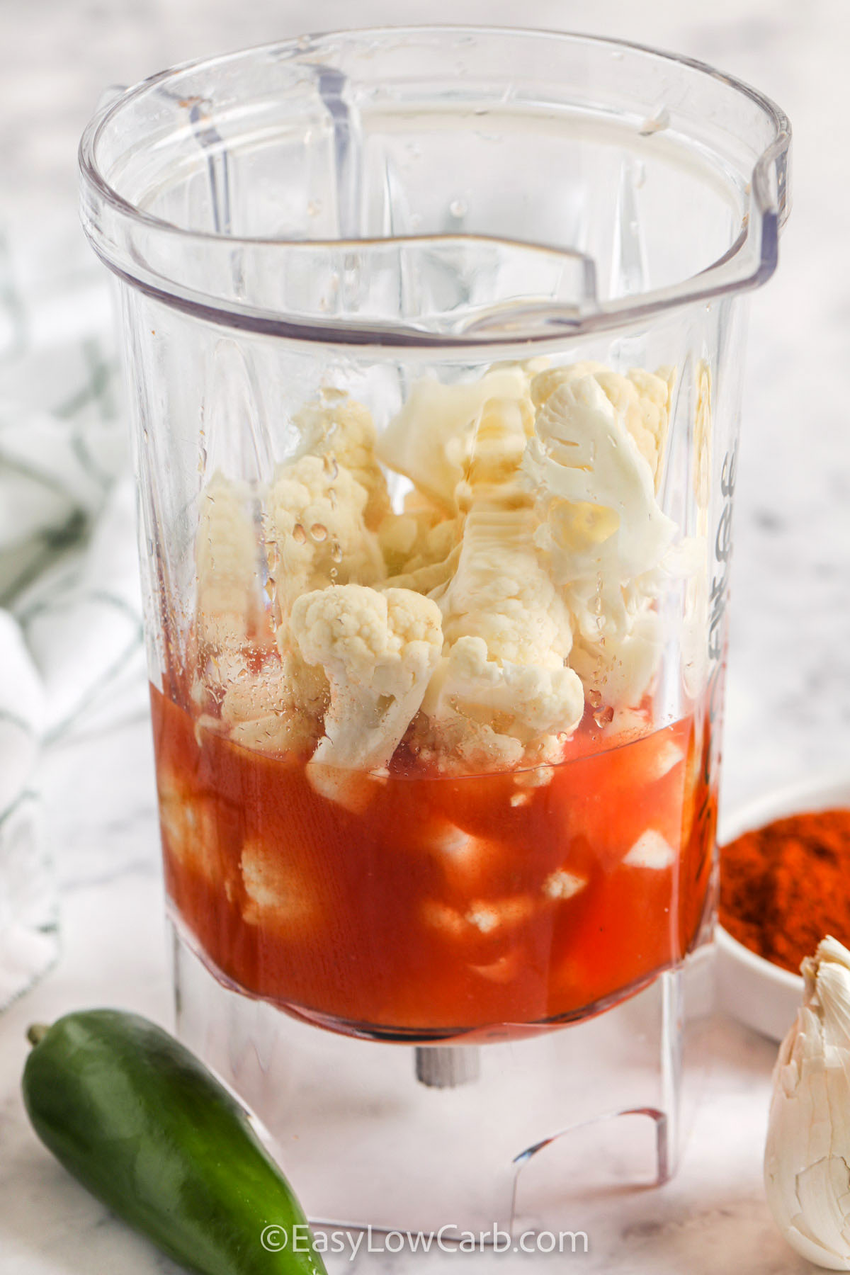 This low carb chili is packed with ground beef, turkey, cauliflower, peppers, and tomatoes for a hearty bowl that stays low in carbs. The cauliflower blends into the sauce for natural thickness, giving you all the comfort of chili without beans. With warm spices and a simmered, slow flavor, it’s an easy recipe perfect for weeknights or big-batch cooking. It reheats beautifully and makes a nourishing, veggie-forward meal. #easylowcarb adding cauliflower and tomato sauce to blender to make Low Carb Chili