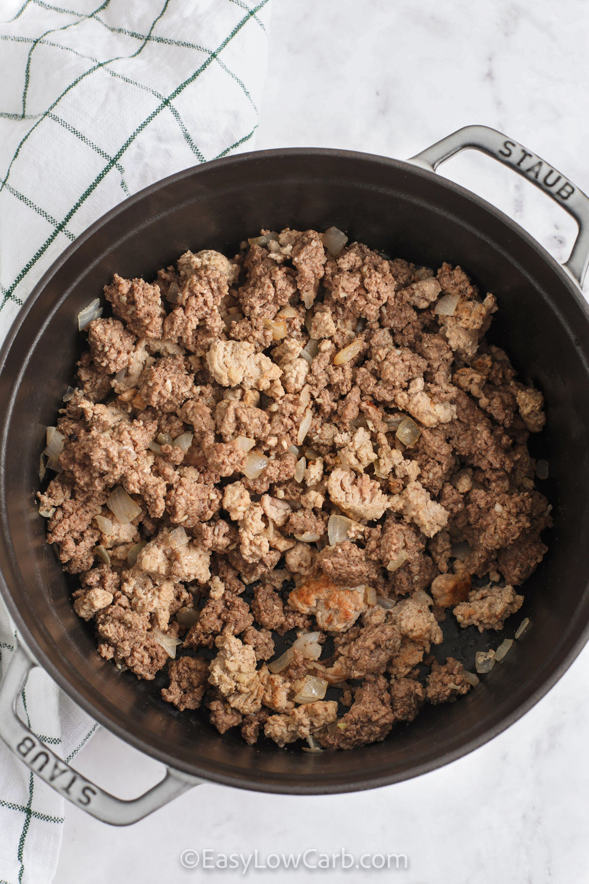 This flavorful low carb chili combines ground beef, turkey, diced tomatoes, cauliflower, and chili spices to create a rich and hearty bowl. Blending a portion of the cauliflower helps the sauce thicken naturally, giving it a classic chili feel without beans. It’s a simple, healthy recipe that works well for meal prep, reheats beautifully, and offers a cozy dinner option packed with veggies and savory comfort. #easylowcarb cooked meat with onions in the pot to make Low Carb Chili