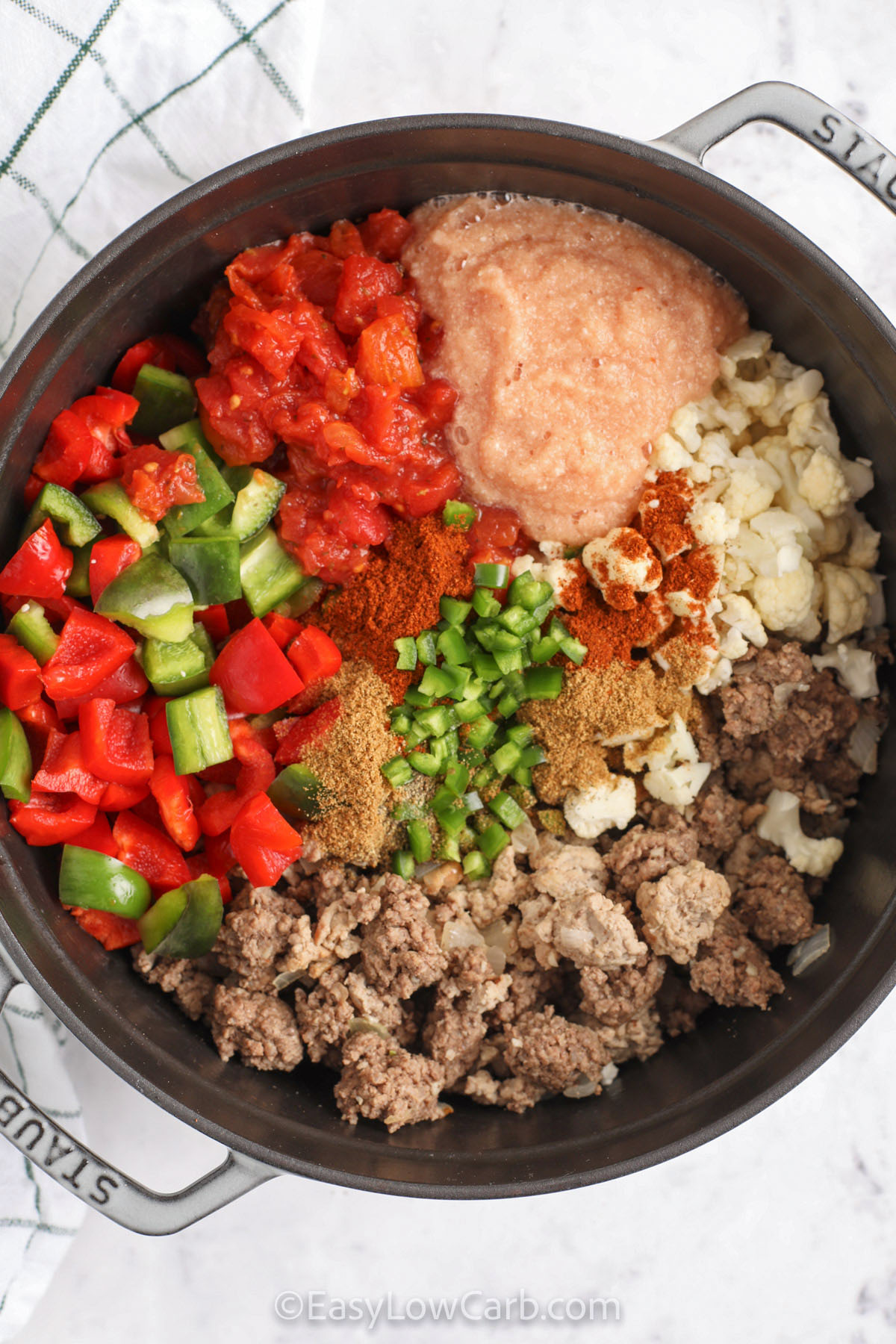 This low carb chili delivers classic comfort with a healthy twist by using cauliflower to replace beans. A blend of beef and turkey creates a rich, savory base, while tomatoes, peppers, and chili seasoning make it flavorful. The blended cauliflower thickens the sauce naturally, keeping every bite hearty yet light. It’s simple to make, freezer-friendly, and perfect for anyone looking for a wholesome, flavorful chili. #easylowcarb adding ingredients together in pot to make Low Carb Chili