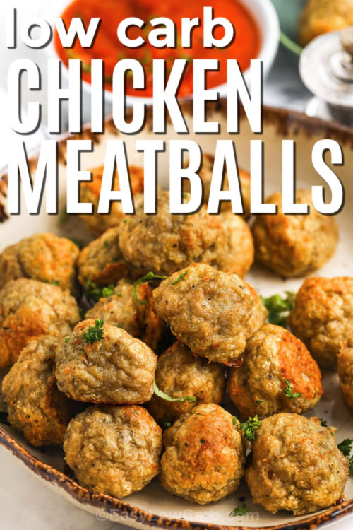 These baked chicken meatballs are made with ground chicken, parmesan, garlic, and almond flour for a tender, juicy texture without breadcrumbs. Everything mixes in one bowl, rolls into bite sized meatballs, and bakes on a sheet pan until golden. Serve them with marinara, zucchini noodles, spaghetti squash, or a simple salad for an easy low carb dinner. They freeze beautifully, so you can prep a double batch for busy nights. #easylowcarb low carb Chicken Meatballs on a plate with a title