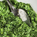Recipe for Creamed Spinach in a bowl with a spoon and a title