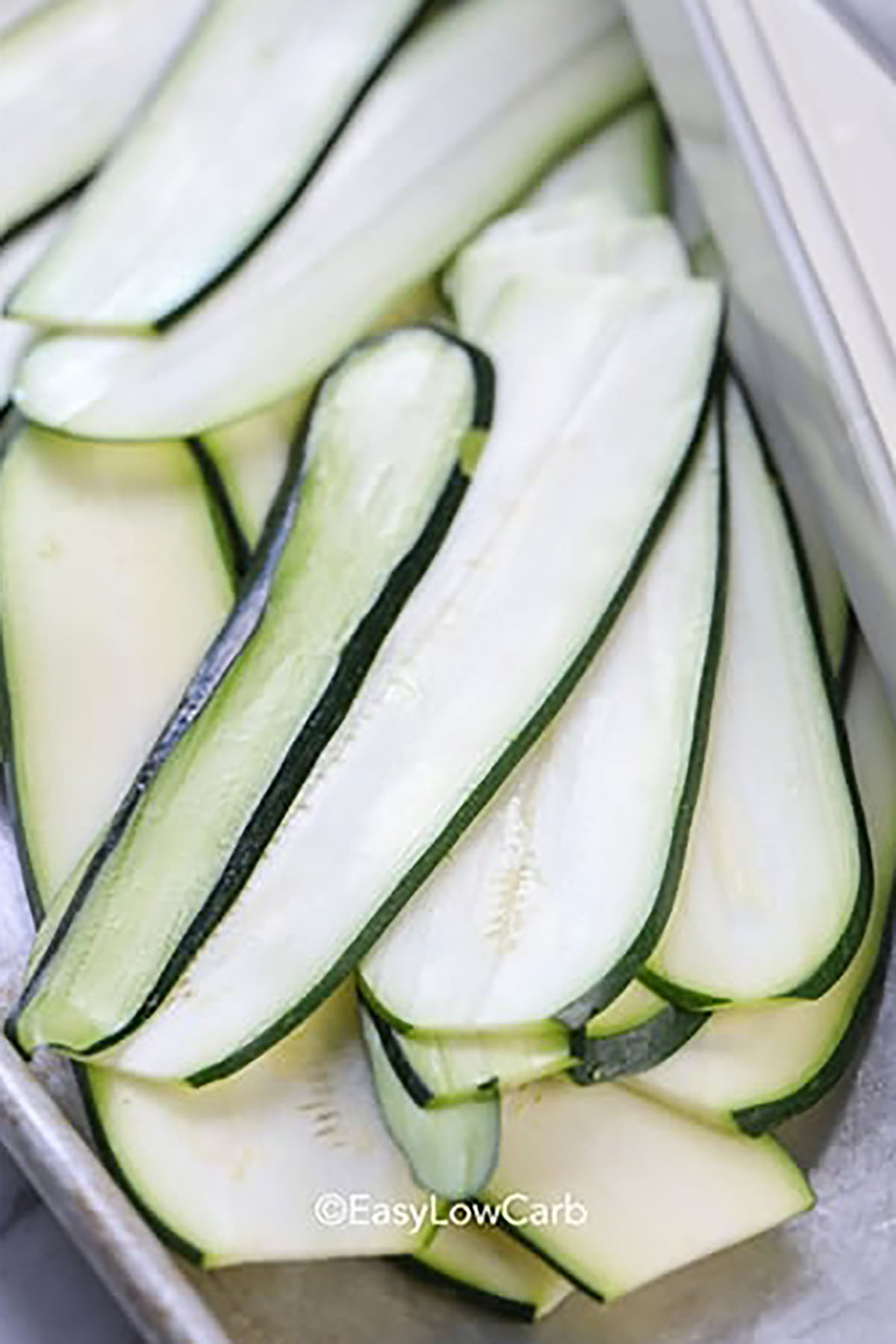 This easy low carb zucchini enchiladas recipe is made for real life, using basic ingredients and a no-fuss method. Start by cutting fresh zucchini into thin strips, then cook shredded chicken with enchilada sauce and roll the filling into the zucchini slices. Nestle them into a baking dish, and cover with more sauce and cheese. Bake until hot and bubbly and you have a satisfying, gluten free meal. It’s light, yet comforting in every bite. #easylowcarb zucchini slices to make Zucchini Enchiladas