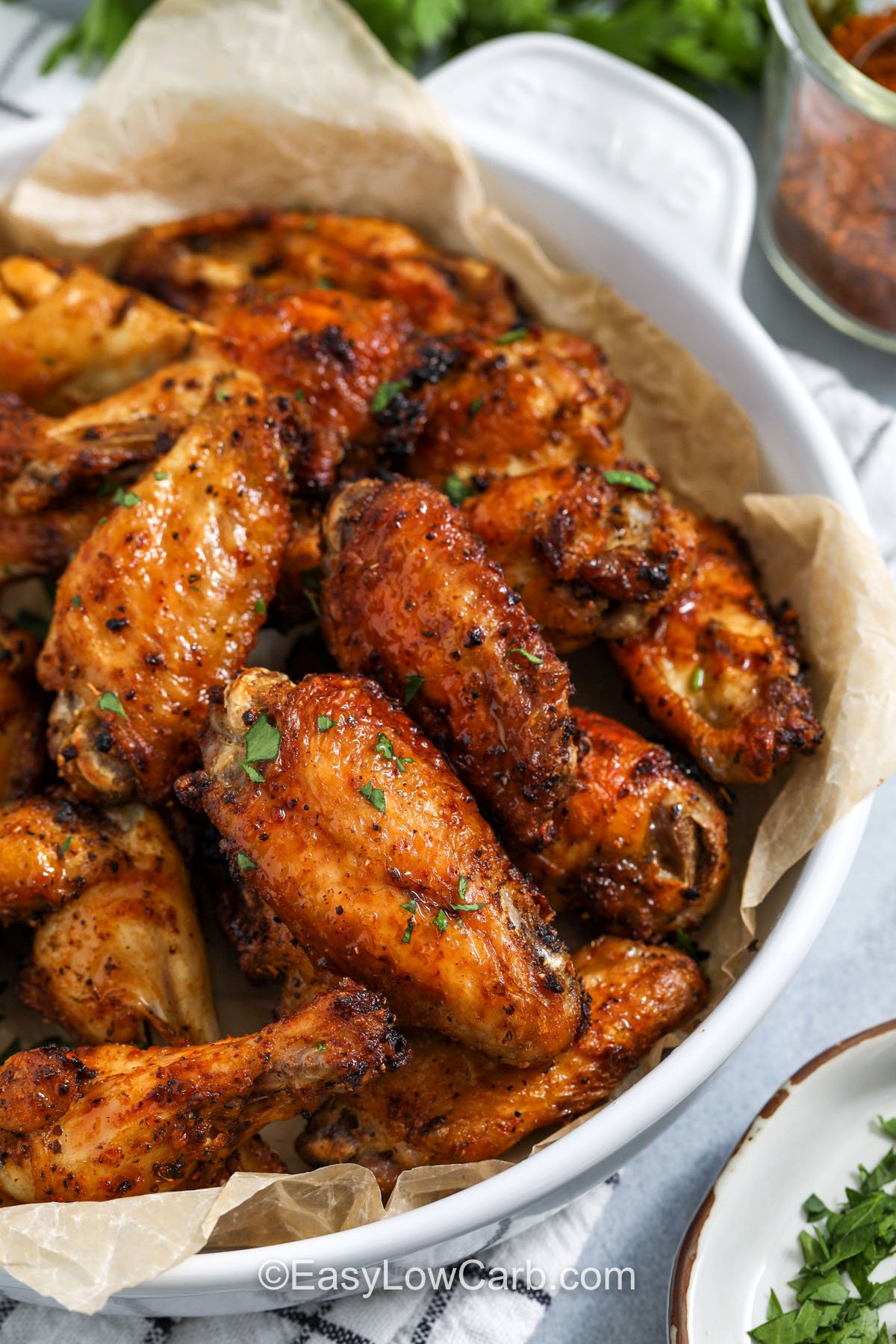 Oven baked Cajun wings are an easy way to feed a crowd with crisp skin and big flavor. Baking on a wire rack keeps hot air moving around the wings so they brown evenly, and flipping halfway through helps the seasoning toast without burning. This Cajun wings recipe is naturally low carb and pairs well with ranch, celery, and cucumbers for a simple platter. #spendwithpennies cajun wings in a white bowl