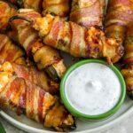 bacon wrapped jalapenos on a plate with dip