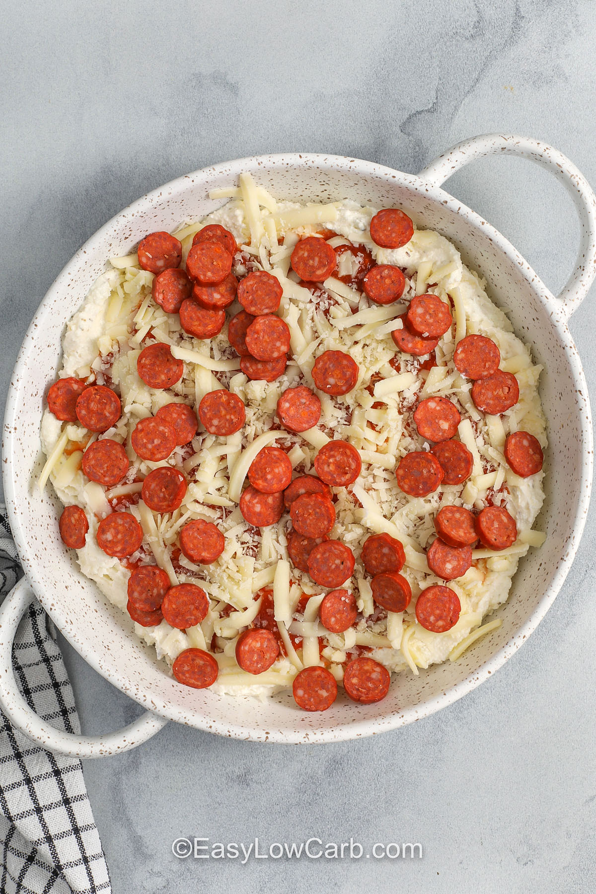 This baked pepperoni dip is an easy, crowd-friendly appetizer that comes together in one bowl and one baking dish. Whipping the cheeses makes the texture extra smooth, and layering the marinara on top keeps the pizza flavor bright. Use low moisture mozzarella for the best melt, and keep most pepperoni on top for crisp edges. It reheats well for quick leftovers. #easylowcarb Pepperoni Dip before baking