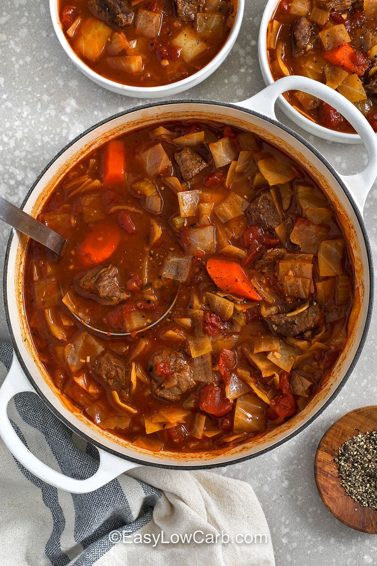 This beef and cabbage soup is made for real life: straightforward prep, one pot, and lots of hands-off simmer time. Beef cubes cook until tender in a tomato broth with vegetable juice, garlic, thyme, and bay leaf. Cabbage goes in at the end for sweet, tender bites that hold up well for leftovers. Store portions for quick lunches, or freeze for an easy dinner later. #easylowcarb taking a ladle full of Beef and Cabbage Soup out of the pot
