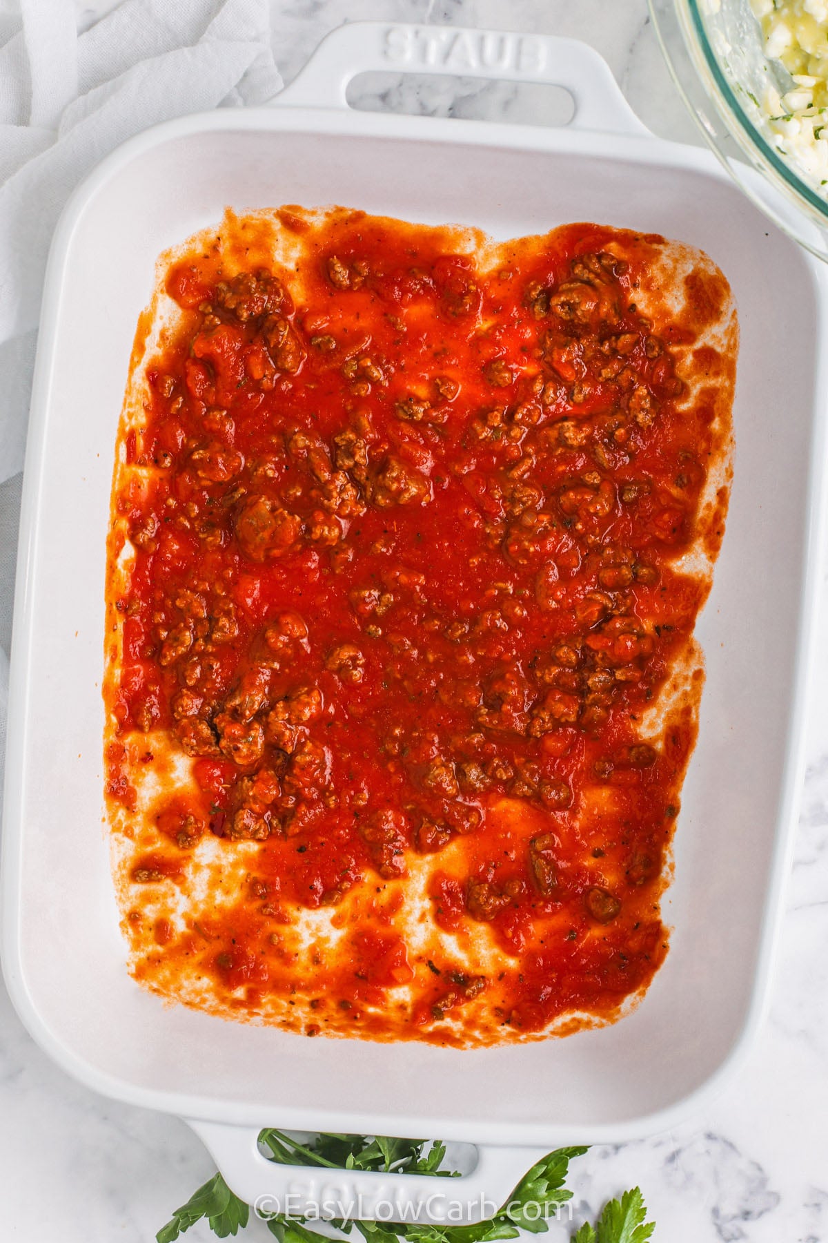 If you want lasagna without noodles, Cabbage Lasagna is the easiest swap that still feels classic. Soft cabbage leaves create tasty layers for meat sauce and creamy cheese filling, and mozzarella melts into a golden cheesy topping. Use a thick low-carb pasta sauce to keep this dish rich and flavorful. Let it rest after baking so the layers set, and each piece serves neatly. #easylowcarb adding meat sauce to casserole dish to make Cabbage Lasagna Recipe