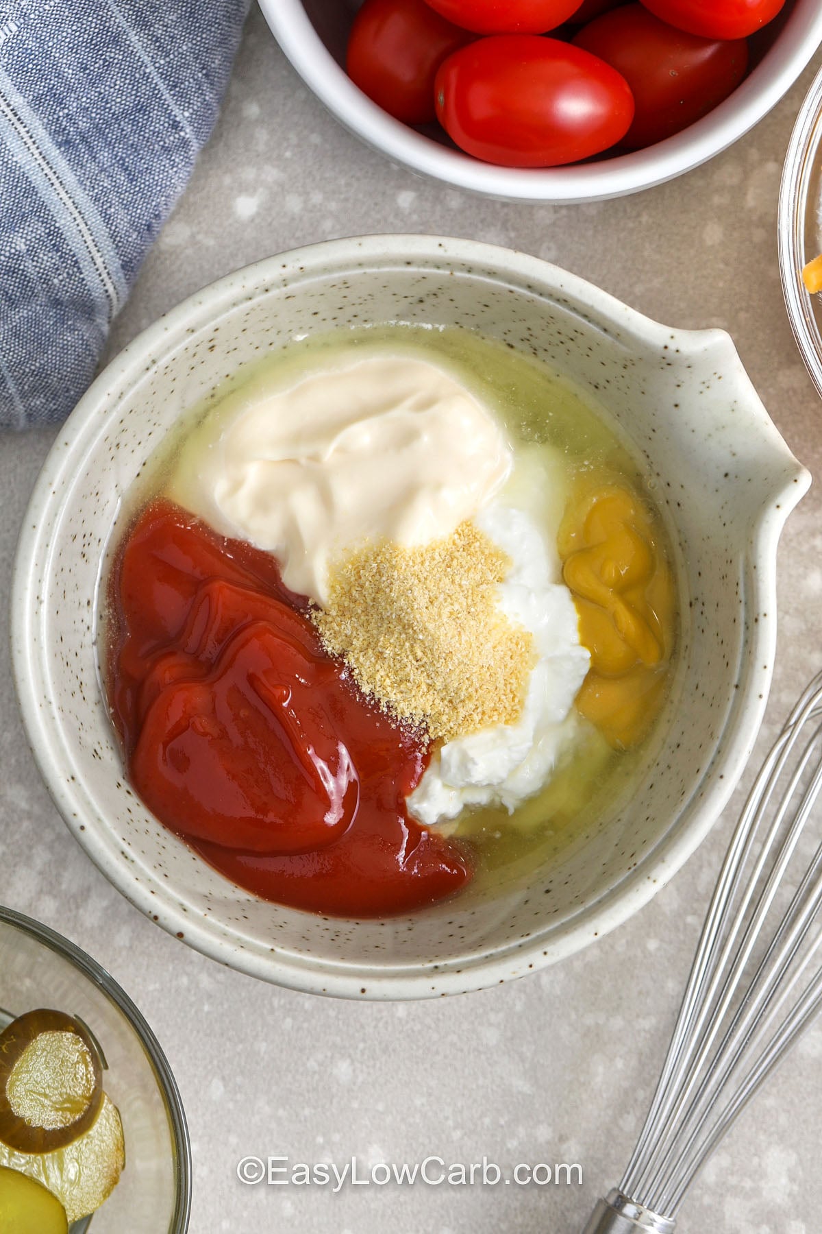 This keto cheeseburger bowl is made for busy nights and meal prep lunches. Cook the seasoned beef in one skillet, then build bowls with crisp lettuce, shredded cheddar, pickles, and juicy cherry tomatoes. The burger sauce dressing is creamy and tangy with mayo, Greek yogurt, sugar-free ketchup, mustard, and pickle juice. Store the components separately so the lettuce stays crunchy until serving. #easylowcarb adding ingredients together to make dressing for Cheeseburger Bowl