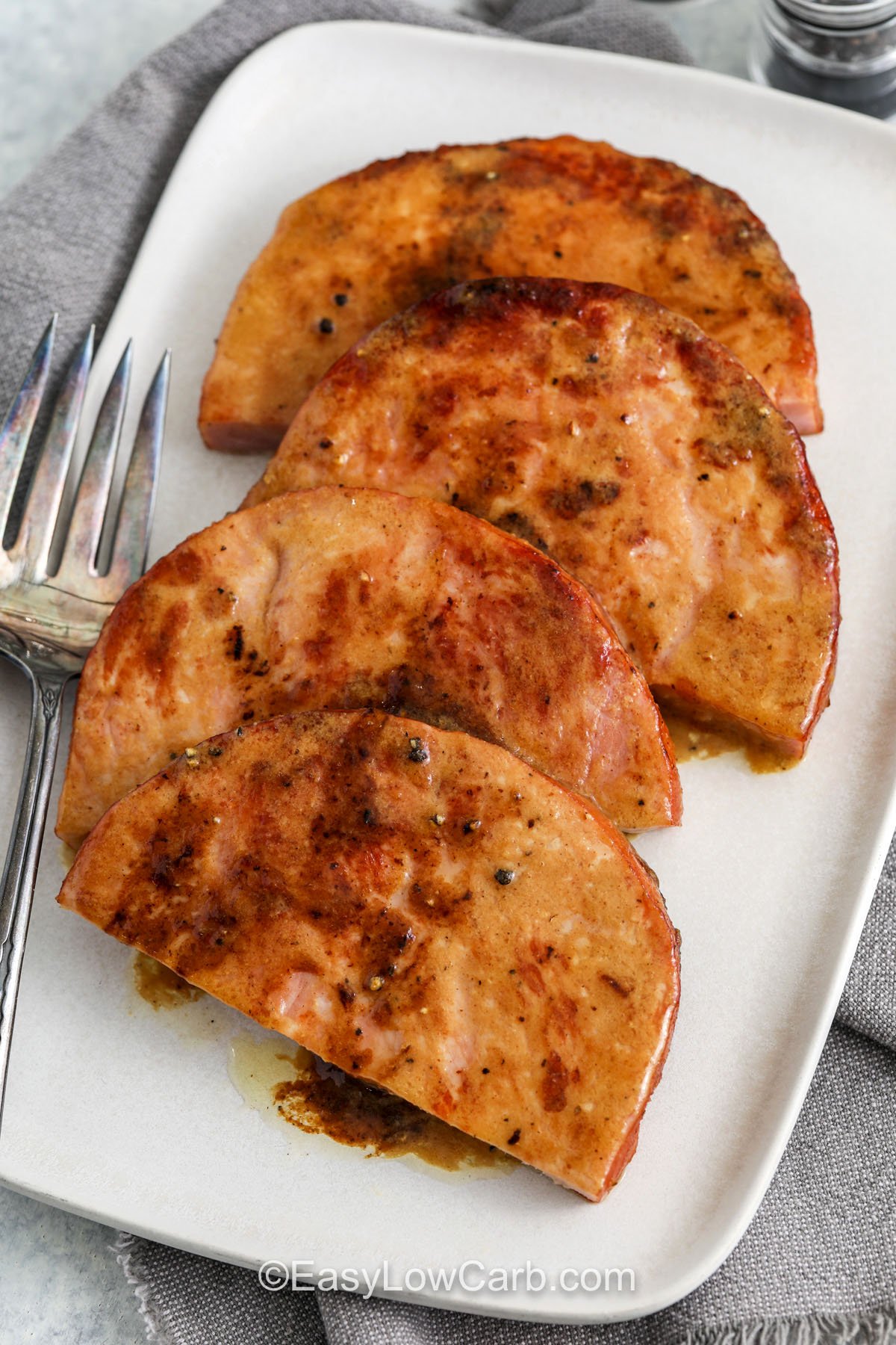 Save this ham steak recipe for busy nights when you want big flavor with minimal prep. A quick skillet sear adds caramelized edges, then a buttery Dijon glaze sweetened with a low carb brown sugar alternative turns glossy and spoonable. Apple cider vinegar keeps the sauce balanced so it tastes bold and not too sweet. Leftovers reheat well and are great chopped into eggs or cauliflower rice for easy meals. #easylowcarb Ham Steak on a plate with a fork