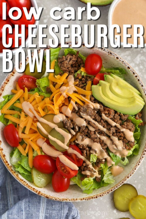 This cheeseburger bowl delivers all the classic burger flavor without the bun. Seasoned skillet ground beef gets layered over crisp lettuce with shredded cheddar, cherry tomatoes, and sliced pickles. The creamy dressing combines mayonnaise, Greek yogurt, sugar-free ketchup, mustard, and pickle juice for a tangy burger sauce finish. Add avocado and bacon for extra richness and crunch, or keep it simple for an easy low carb dinner. #easylowcarb low carb Cheeseburger Bowl with writing