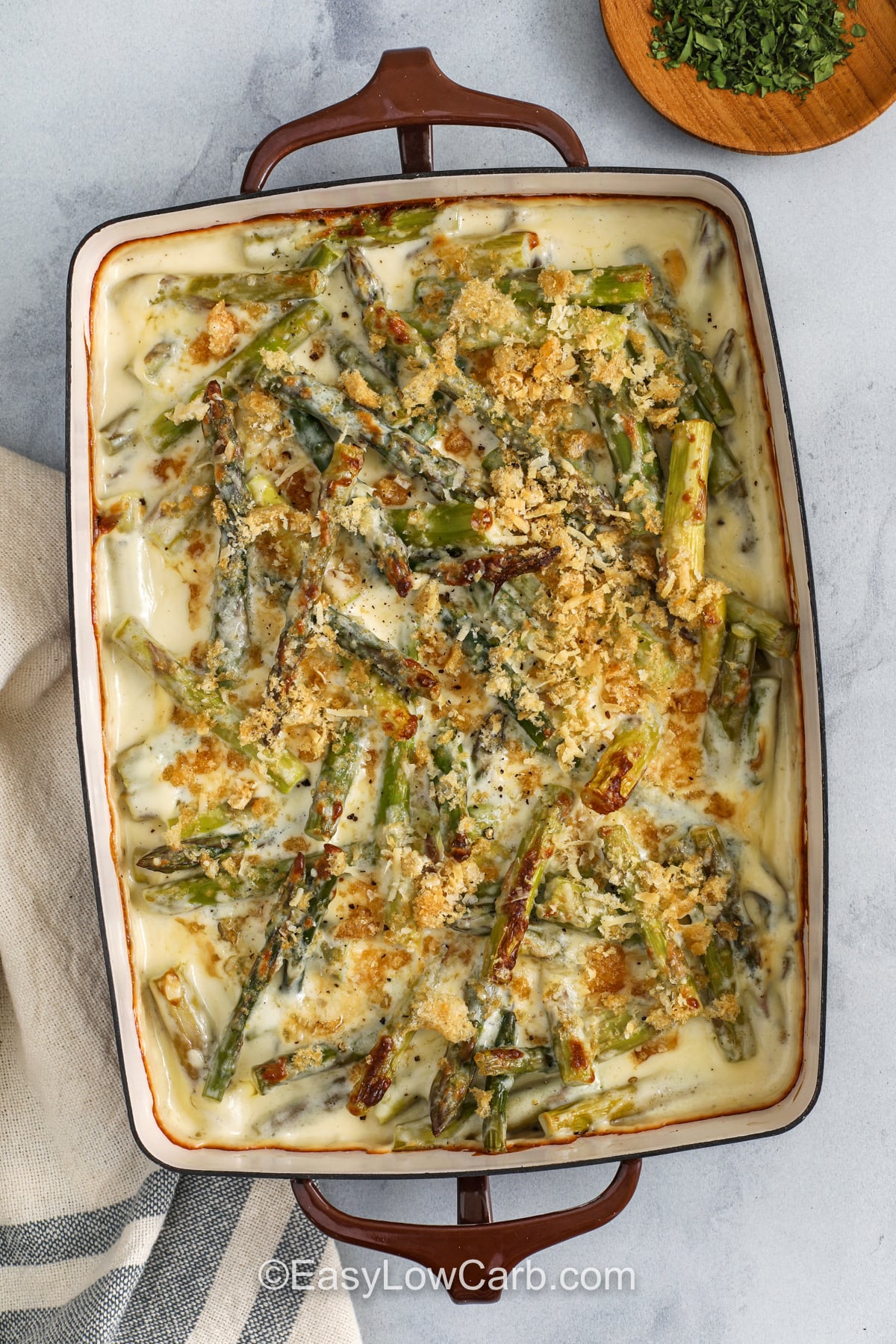 This keto asparagus casserole bakes up bubbly with a rich cheese sauce that clings to every bite. Garlic, cream cheese, and heavy cream create a silky base, and sharp cheddar or gruyere melts in for big flavor. Finish with parmesan and crushed pork rinds for a crisp topping. It is a fast, satisfying side dish that pairs well with grilled chicken, pork, or salmon. #easylowcarb casserole dish of Asparagus Casserole