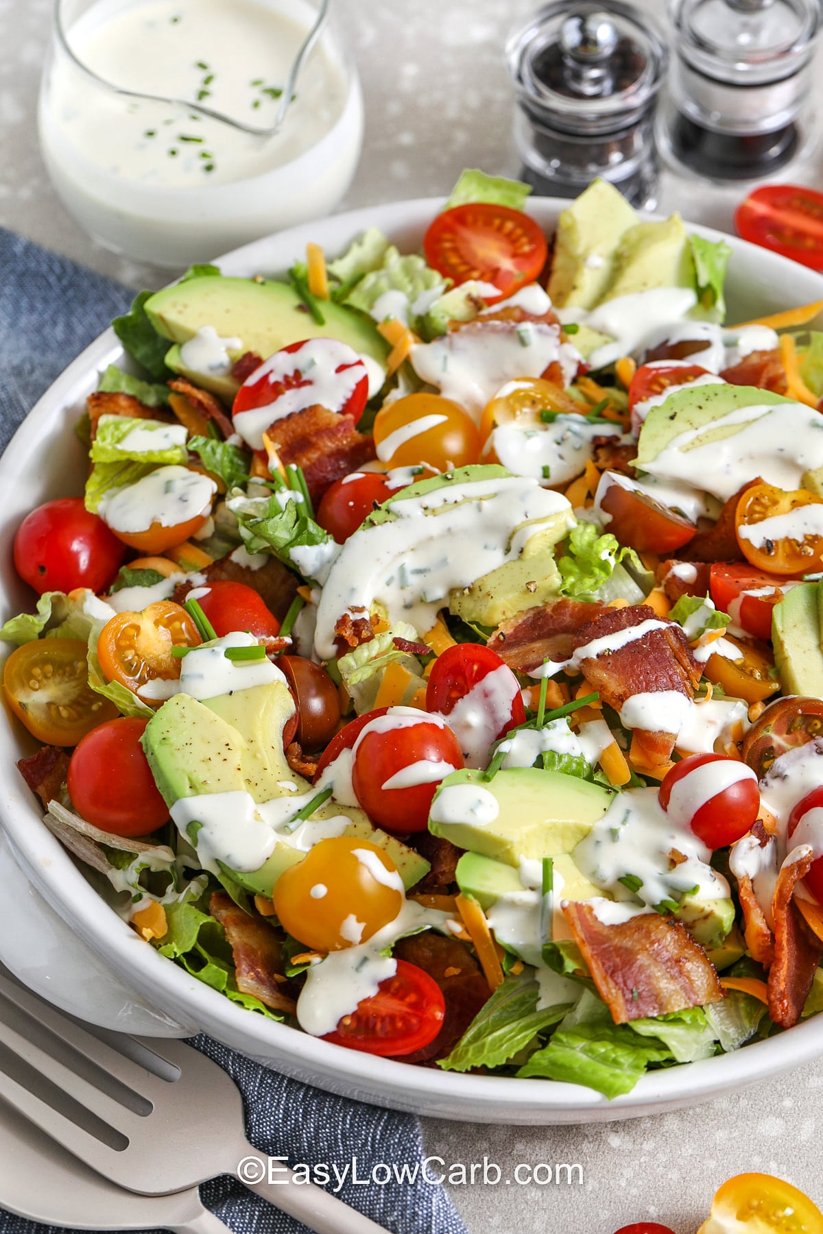 This chopped BLT salad is packed with texture and flavor, from crisp romaine to smoky bacon and sweet tomatoes. Avocado adds creamy richness and cheddar adds a sharp bite. The salad dressing blends mayonnaise, Greek yogurt, lemon juice, garlic powder, and chives for a smooth, tangy drizzle. Serve it right away for peak crunch, or prep components separately for later. #easylowcarb BLT salad in a white bowl