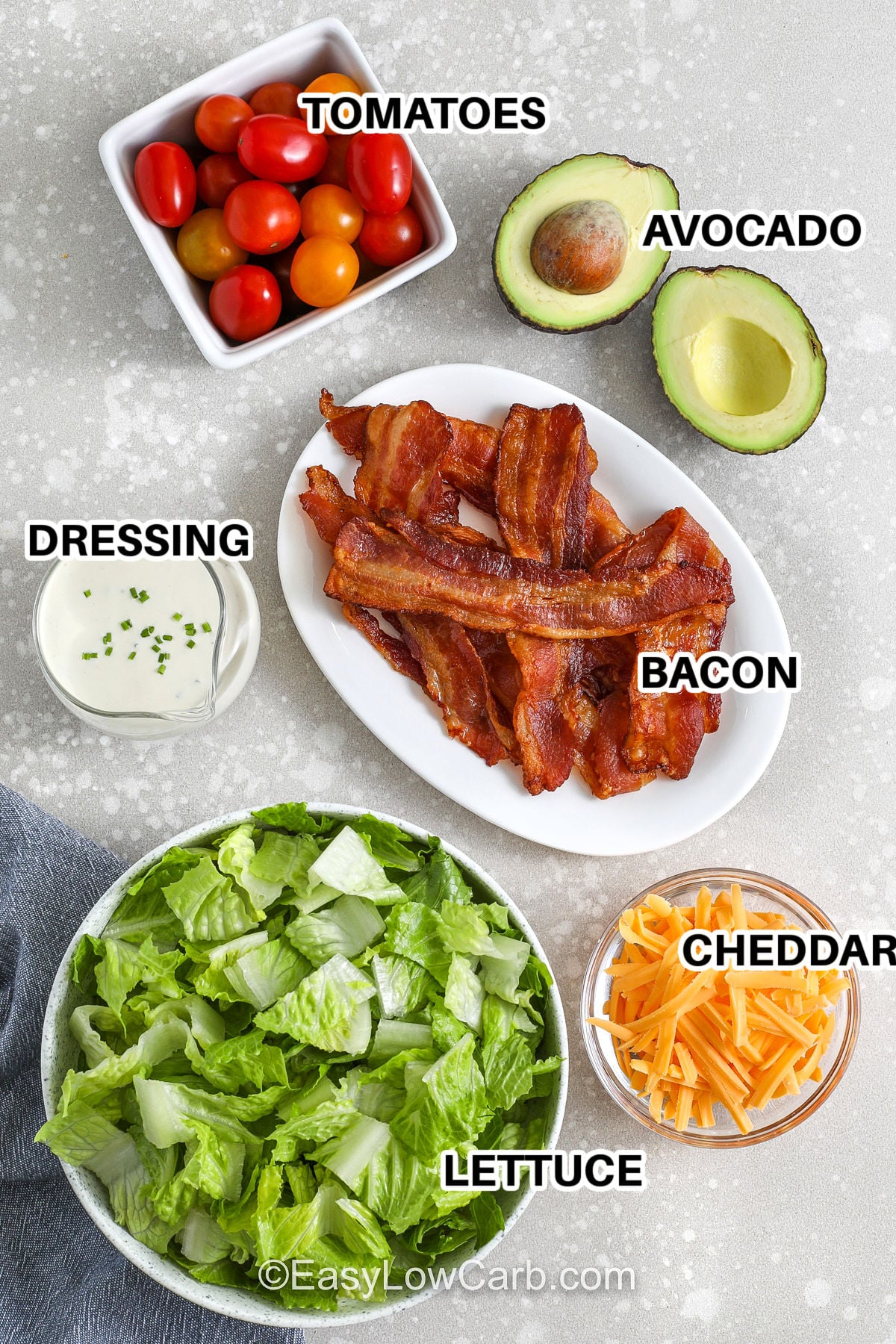 This BLT salad without croutons is still loaded with comfort-food flavor thanks to bacon, cheddar, and avocado. The creamy BLT salad dressing has mayo, Greek yogurt, lemon, Dijon, and chives for a tangy, ranch-like vibe that pairs perfectly with tomatoes. Use pre-washed greens and cooked bacon to make it an easy low carb meal in minutes, perfect for meal prep bowls. #easylowcarb labelled BLT ingredients