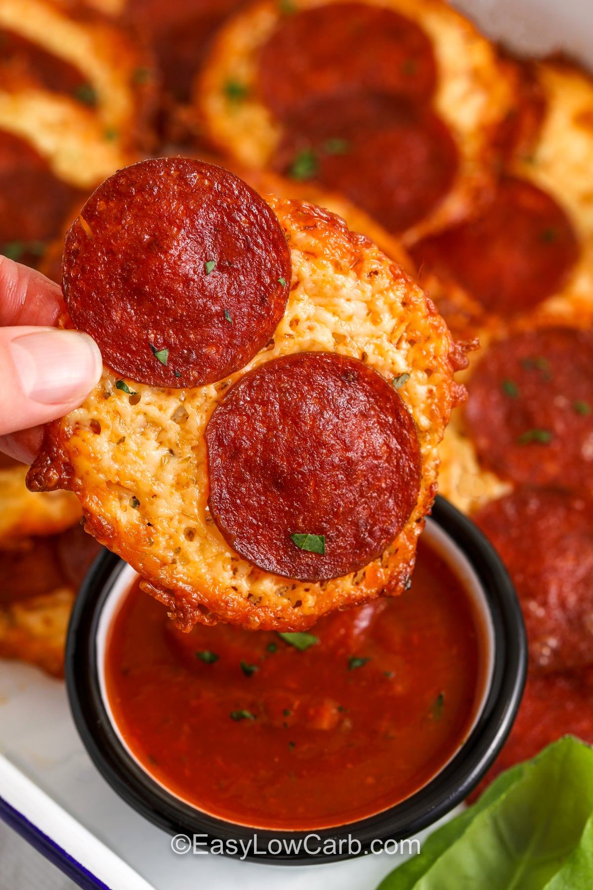 Pizza chips are an easy low carb appetizer made from mozzarella, pepperoni, and simple seasonings. The trick is spacing the cheese mounds so they do not merge, and baking until the edges are browned and golden. Let the chips cool before moving them so they crisp properly. Serve with low carb marinara sauce for dipping, and you have a snack that tastes like pepperoni pizza with a crunchy finish. #easylowcarb dipping Pizza Chips in marinara sauce