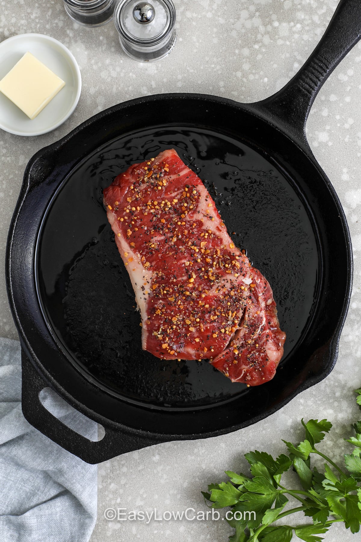 This steak and eggs breakfast recipe is perfect for mornings when you want something hearty, simple, and low carb. A well-seasoned steak cooks in olive oil and butter for a flavorful crust, while the eggs pick up all the savory bits left in the pan. Whether you use ribeye, strip, or sirloin, this high protein breakfast is easy to adapt and even better with sliced avocado or zucchini. #easylowcarb seasoned steak on a pan to make Steak and Eggs Breakfast