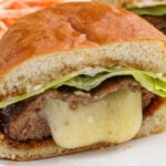 An assembled cheese stuffed burger cut in half on a plate