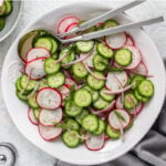 Cucumber radish salad prepared in a bowl with serving utensils