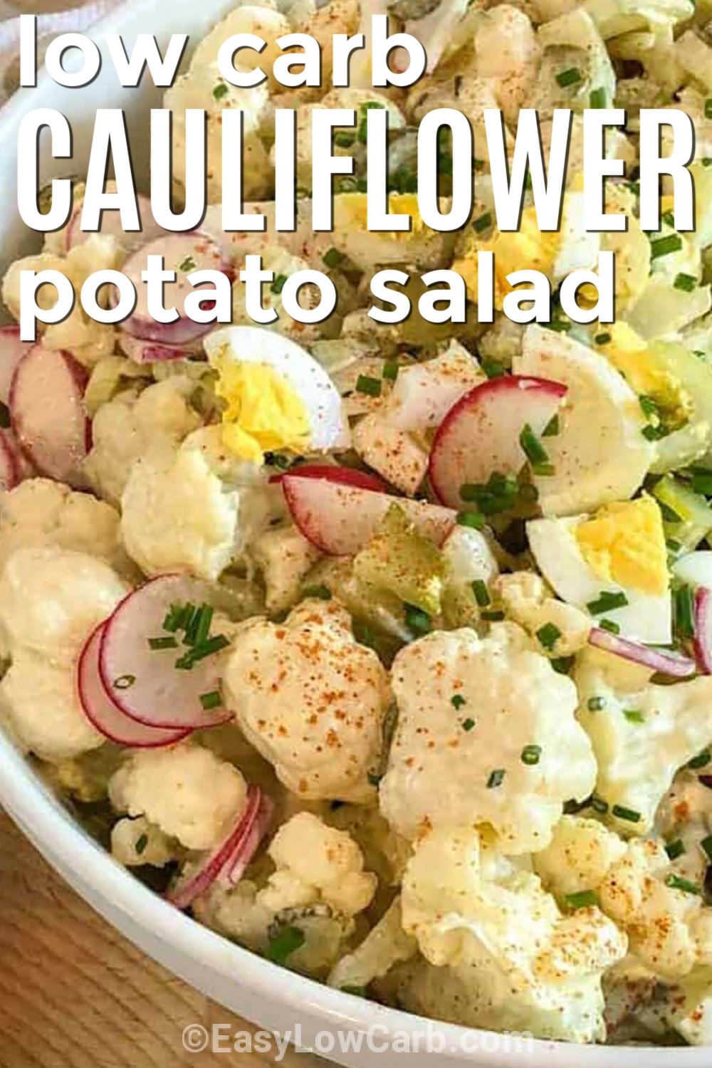 Cauliflower potato salad is the creamy, tangy side dish you will want to bring to every cookout and family dinner. Tender cauliflower replaces potatoes while crisp celery, radishes, dill pickles, green onions, and eggs add plenty of flavor and crunch. The rich mustard mayo dressing makes every bite taste like the classic you love, but as a delicious low-carb potato salad. Add this easy keto side dish to your menu and give it a try today. #easylowcarb plated Cauliflower Potato Salad with a title