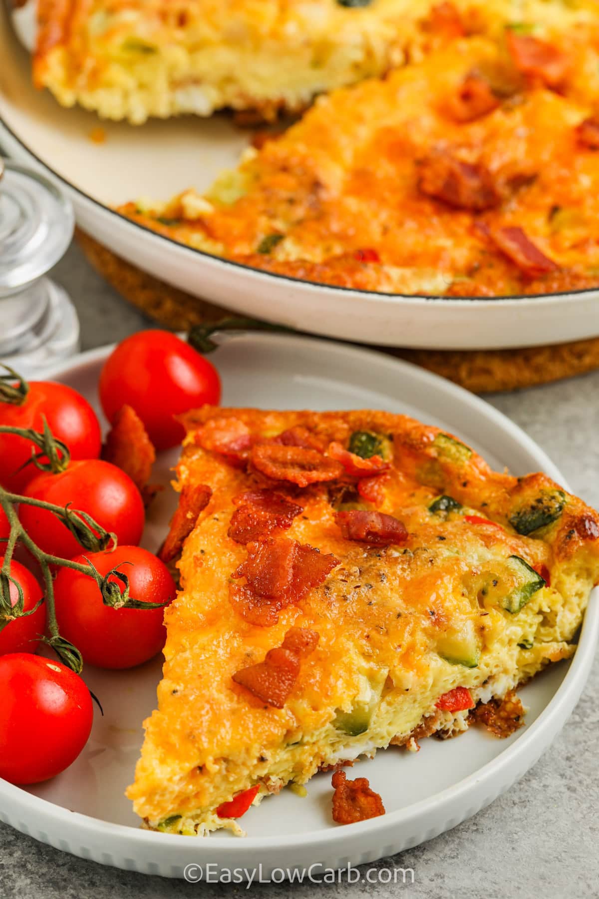 Enjoy zucchini frittata as a delicious way to start the day with bacon, eggs, and fresh vegetables. Every slice is loaded with cheddar cheese, tender zucchini, and savory flavor in every bite. This zucchini frittata recipe is easy to serve for brunch, meal prep, or breakfast for dinner. Make a skillet today and see why it is a family favorite. #easylowcarb slice of Zucchini Frittata on a plate
