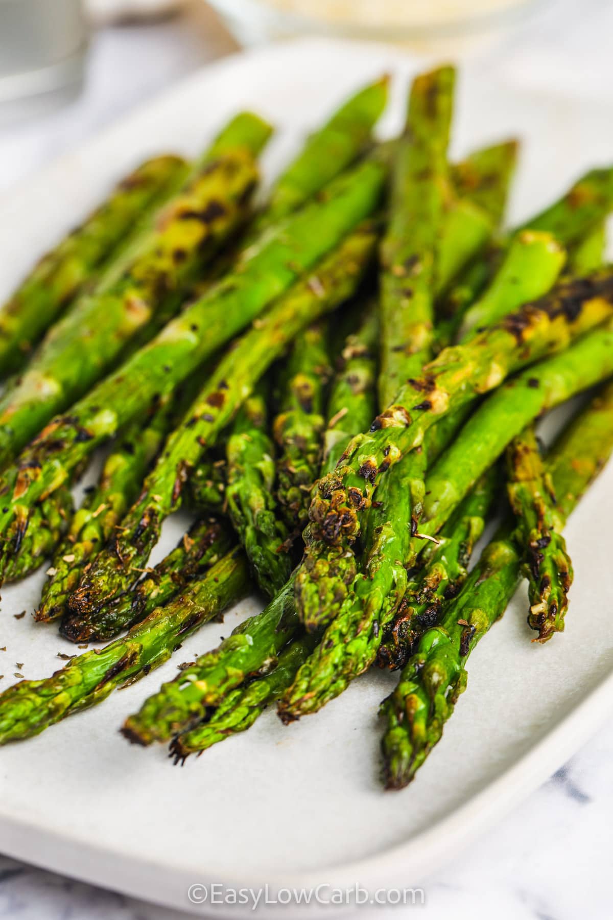 Grilled asparagus recipe is perfect when you want a fresh side without a long list of ingredients. The asparagus is seasoned simply, then grilled until tender with nicely browned edges. Lemon juice adds a bright pop of flavor that makes this vegetable side stand out. It is delicious with seafood, chicken, burgers, or almost any meal from the grill. Try this easy asparagus recipe and bring more vegetables to the table. #easylowcarb Grilled Asparagus Recipe on a plate