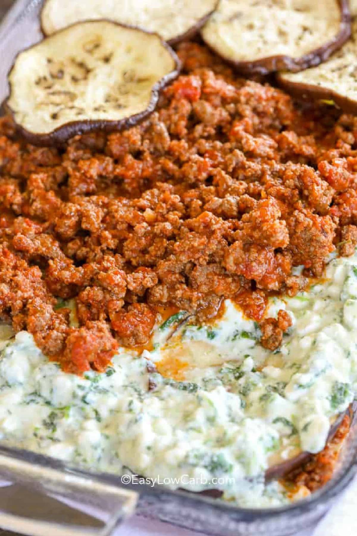 When you crave comfort food, this eggplant lasagna recipe delivers with layers of tender eggplant, seasoned beef, creamy cheese, spinach, and tomato sauce. Skipping the traditional noodles keeps this casserole low in carbs while still giving you plenty of hearty flavor. The melted mozzarella on top brings everything together for a family-friendly dinner. If you love cheesy casseroles, this one belongs on your menu. Make it today. #easylowcarb adding layers to dish to make Eggplant Lasagna