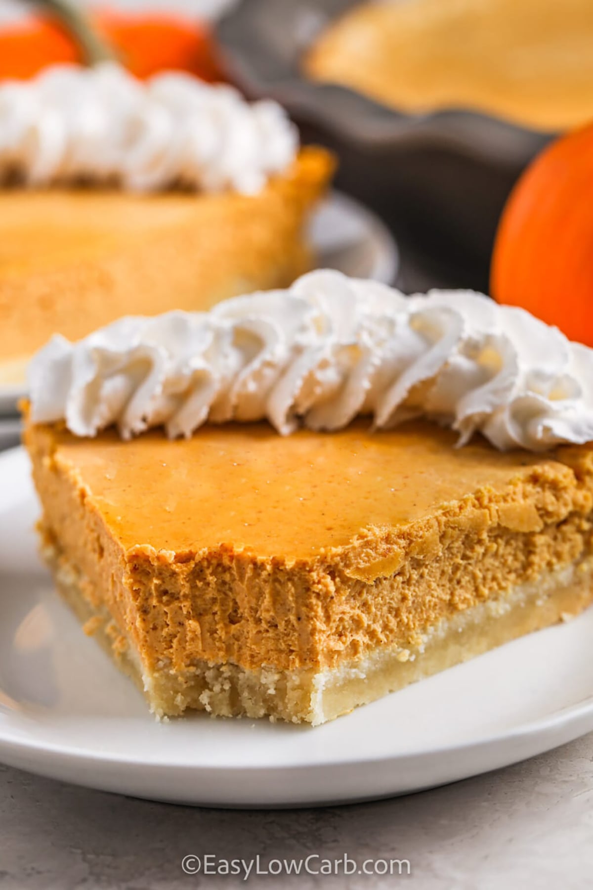 This keto pumpkin cheesecake is a creamy make-ahead dessert made with pumpkin puree, softened cream cheese, warm spices, and a simple baked almond flour crust. The filling comes together quickly in a blender or food processor, then bakes until set before chilling. It is especially convenient for Thanksgiving because dessert can be finished well before dinner begins. Save this keto pumpkin cheesecake recipe for fall entertaining. #easylowcarb slice of Keto Pumpkin Cheesecake with a bite taken out