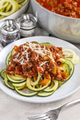 a plate of zucchini spaghetti with meat sauce and Parmesan.
