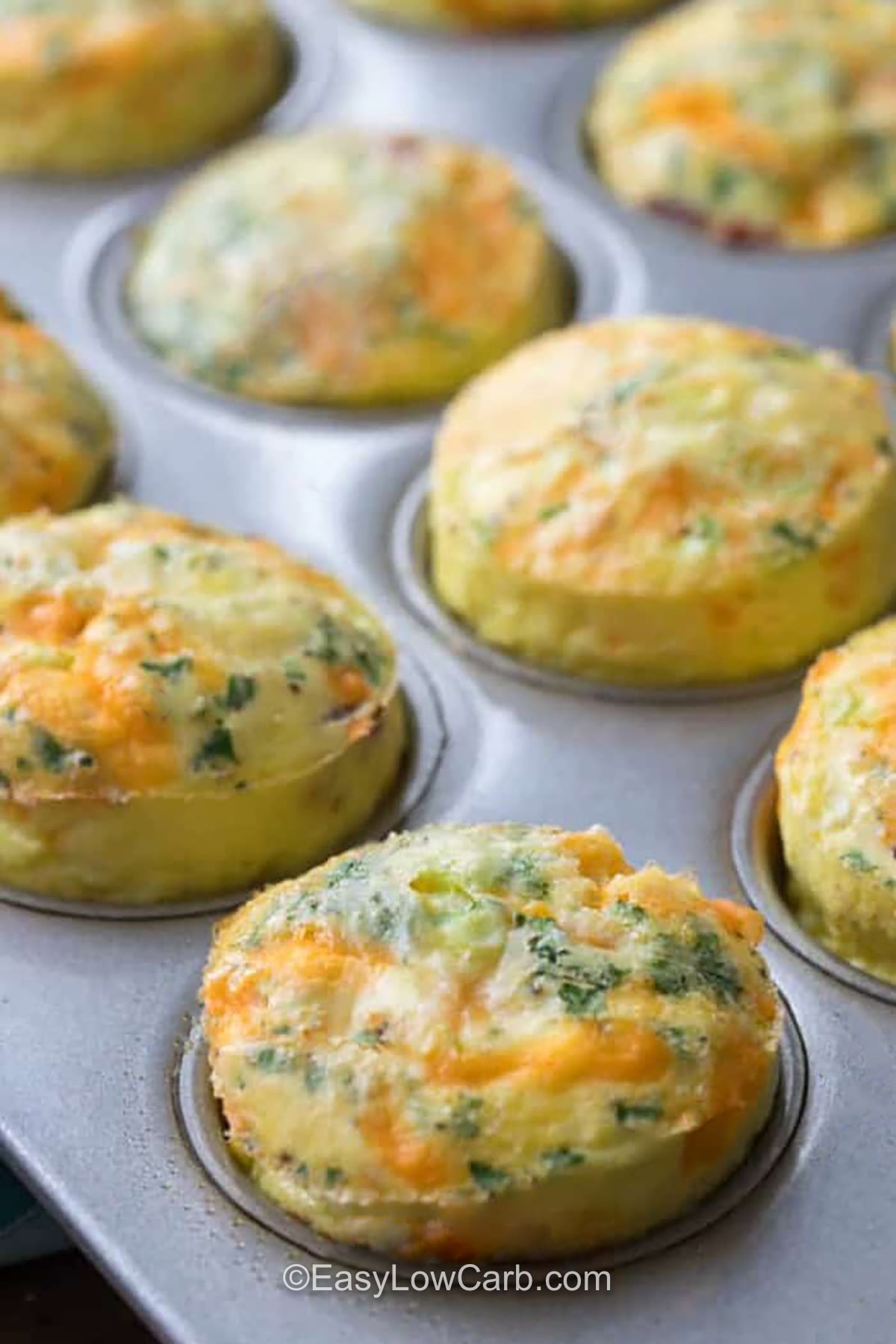 Bacon and egg muffins make a hearty breakfast with simple ingredients you likely already have. Cheddar cheese, cooked bacon, green onions, and fresh herbs add savory flavor to baked eggs. These low carb breakfast muffins are easy to make ahead and simple to reheat when you need a quick meal. Keep a few in the fridge or freezer for busy days and easy snacking. Give this simple egg muffin recipe a try today. #easylowcarb muffin tin with cheesy Bacon and Egg Muffins