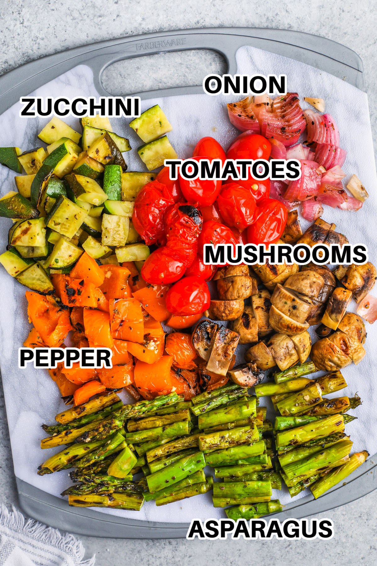 This grilled vegetable salad is a colorful combination of charred summer vegetables, creamy feta, and crunchy toasted nuts. Lemon juice and Italian seasoning flavor the zucchini, asparagus, peppers, tomatoes, and onion before they hit the grill. A light balsamic dressing is added while the vegetables are warm so every bite absorbs more flavor. It is an easy 20-minute side for meal prep or entertaining. Save the recipe and make it this summer. #easylowcarb onion , zucchini , tomatoes , mushrooms , pepper , asparagus with labels to make Grilled Vegetable Salad