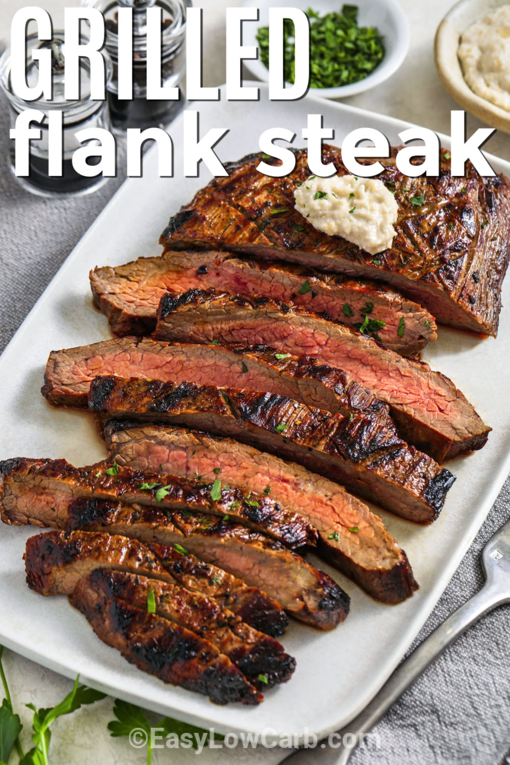 Grilled flank steak brings tender, juicy flavor to your next family meal. This simple recipe starts with an easy homemade marinade that adds plenty of flavor to lean steak. After grilling, let the meat rest before slicing it across the grain for the best texture. Serve it with grilled vegetables, cauliflower rice, or a crisp salad. Any leftovers make an easy addition to lunch bowls and lettuce wraps. Make this tasty recipe soon. #easylowcarb plated Grilled Flank Steak with writing