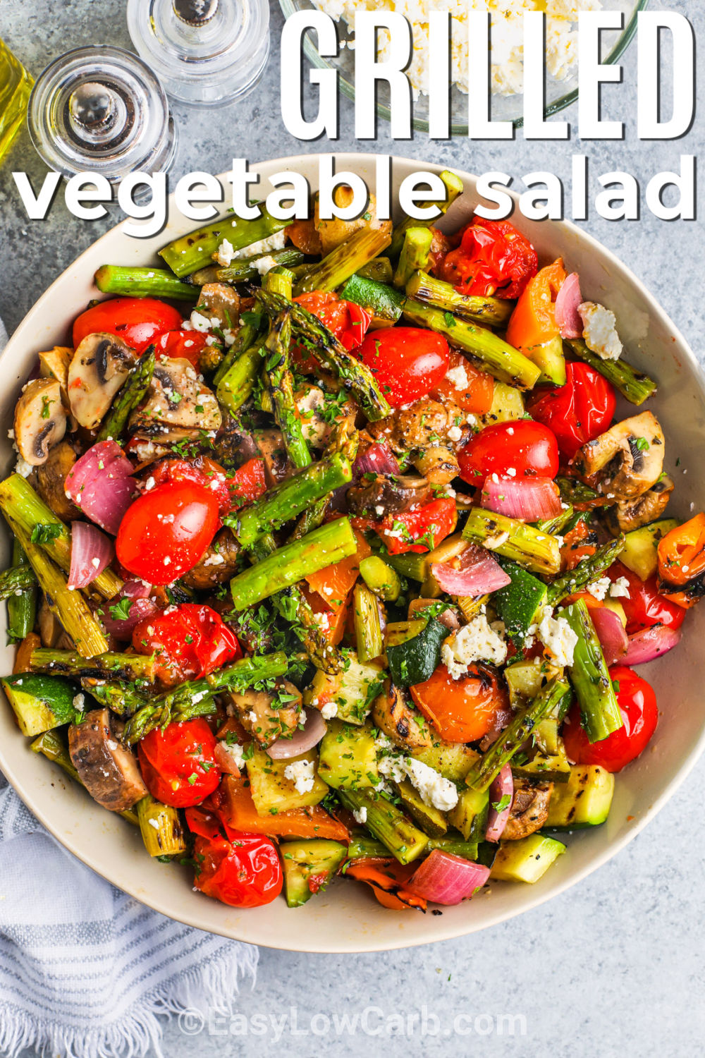 This low carb grilled vegetable salad turns simple summer produce into a smoky and satisfying side dish. Zucchini, peppers, asparagus, onion, and tomatoes cook quickly on the grill, so the entire recipe is ready in about 20 minutes. A fresh parsley balsamic vinaigrette coats the warm vegetables, while crumbled feta and pine nuts add a savory finish. Serve it warm or at room temperature, and save this easy recipe for grilling season. #easylowcarb top view of plated Grilled Vegetable Salad with a title