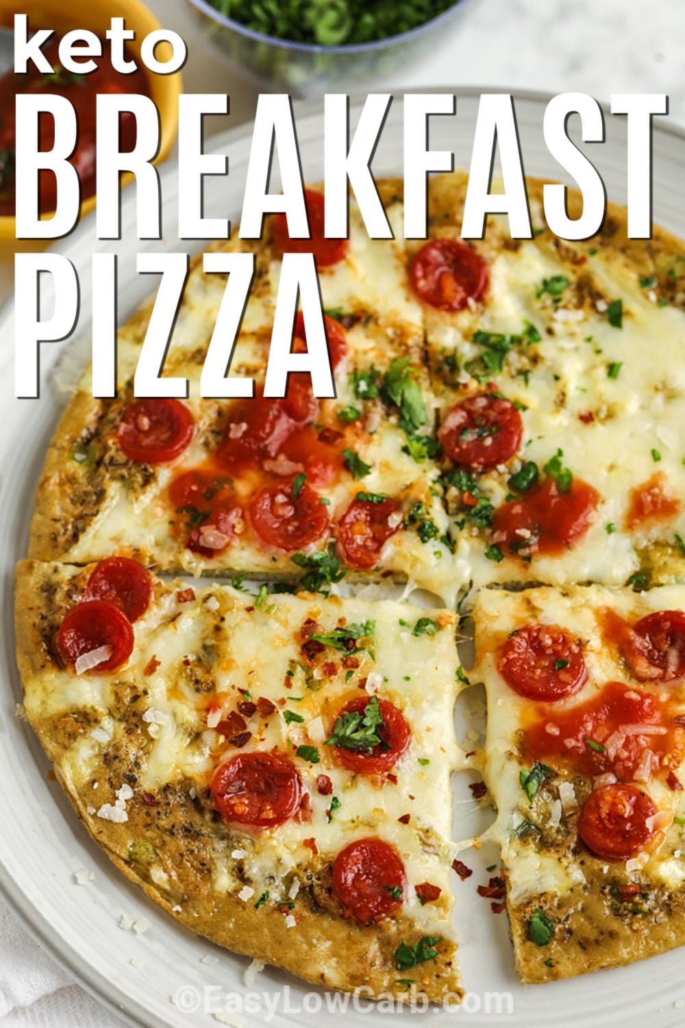 This crustless keto breakfast pizza packs familiar pizza flavor into an easy single-serving breakfast. A tender egg crust is seasoned with oregano, then topped with mozzarella and pepperoni before a quick broil makes everything hot and melty. Serve low-carb tomato sauce alongside for dipping so the egg base stays firm. It is simple, practical, and ready in about 15 minutes. Save this cheesy keto breakfast recipe to make soon. #easylowcarb Keto Breakfast Pizza on a plate sliced with a title