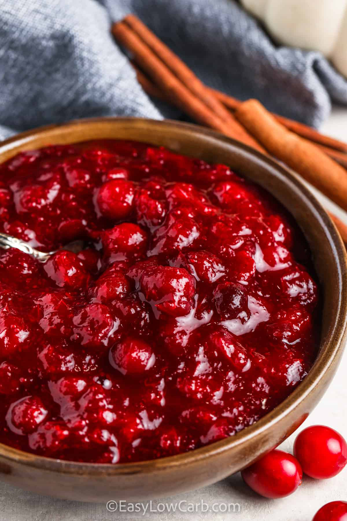 bowl of Keto Cranberry Sauce with cinnamon sticks beside it.