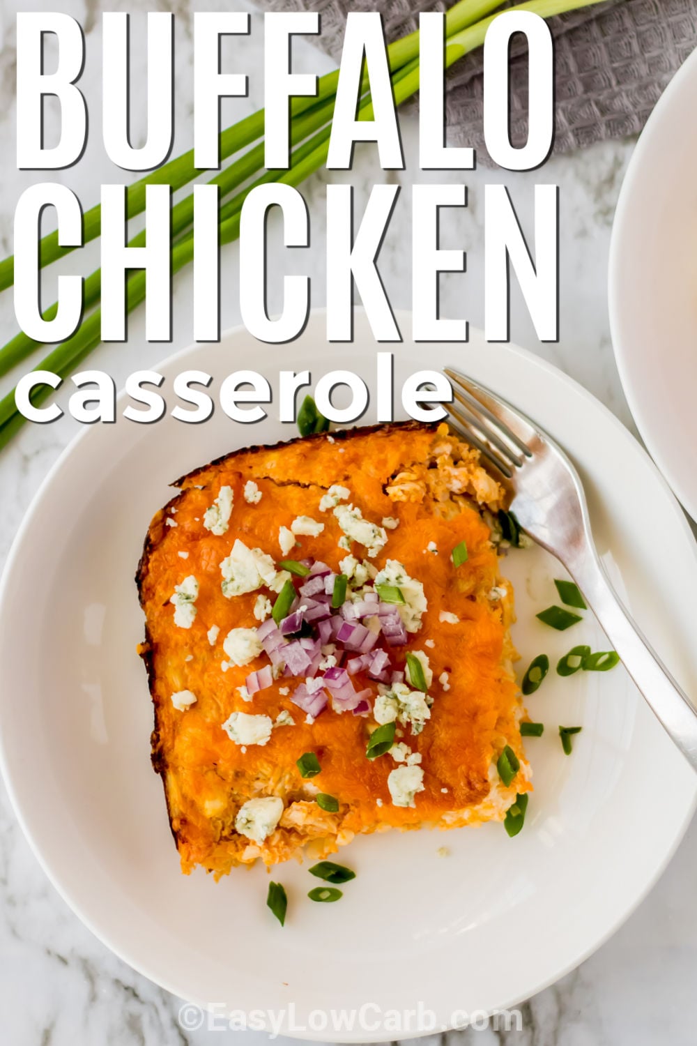 This keto buffalo chicken casserole brings together tender chicken, cauliflower rice, and bold buffalo sauce. Creamy cheese and tangy sour cream balance the heat, while cheddar adds a savory finish. It is an easy low-carb casserole that makes great use of cooked or leftover chicken. Add blue cheese and green onions on top for even more buffalo-style flavor. Bring this spicy chicken casserole to the table for an easy dinner. #easylowcarb cheesy Keto Buffalo Chicken Casserole slice on a plate with writing.