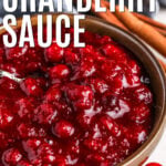 Keto Cranberry Sauce in a bowl with a spoon with cinnamon sticks beside it and writing.