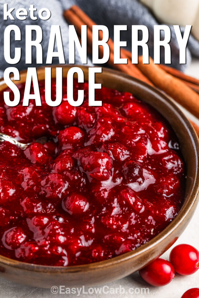 Keto Cranberry Sauce in a bowl with a spoon with cinnamon sticks beside it and writing.