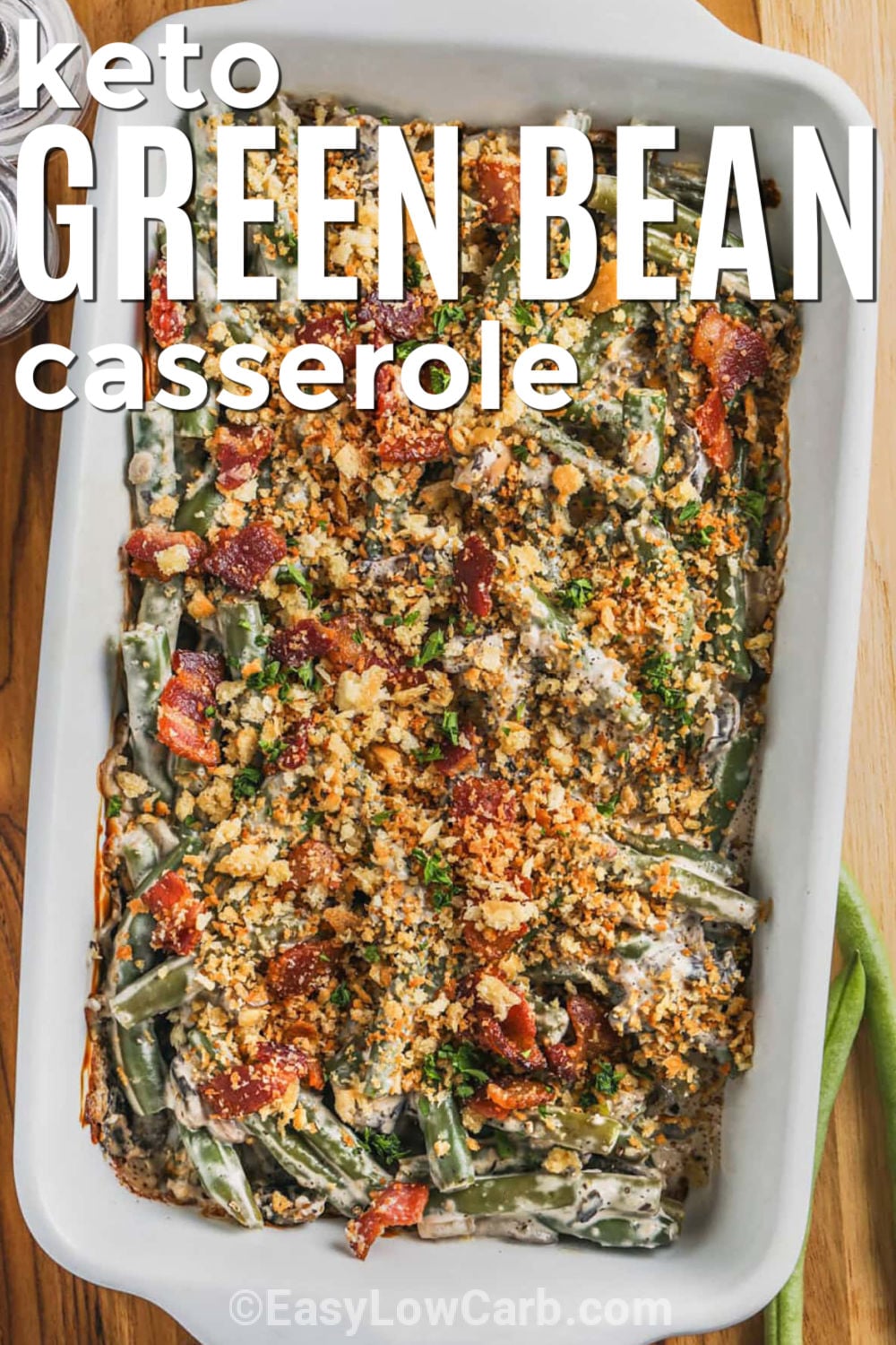 Keto green bean casserole is a creamy, savory side dish that makes any holiday meal feel extra special. Tender green beans are tossed with mushrooms, garlic, bacon, cream cheese, and Parmesan for rich flavor in every bite. This low carb green bean casserole is easy to prepare and can even be assembled ahead of time. Bring a classic holiday favorite to your table with fewer carbs. Try this recipe today. #easylowcarb Keto Green Beans Casserole in the dish with writing.