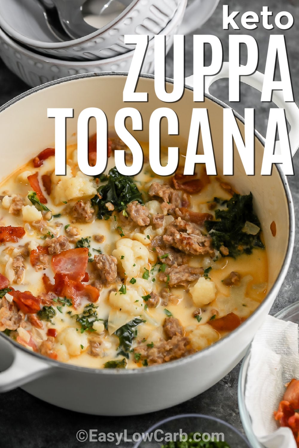 Cozy Keto Zuppa Toscana brings creamy, savory flavor to the dinner table with simple ingredients. Italian sausage and bacon add richness, while cauliflower and kale make this low carb soup hearty and filling. A creamy chicken broth ties everything together for a comforting meal the whole family can enjoy. Serve it with keto crackers or a fresh salad for an easy dinner. Make a pot of this delicious soup today. #easylowcarb pot of Keto Zuppa Toscana with a title.