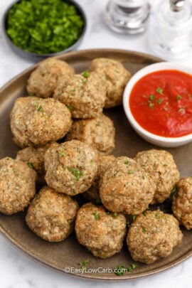 Ground turkey meatballs on a brown serving plate with marinara dipping sauce.